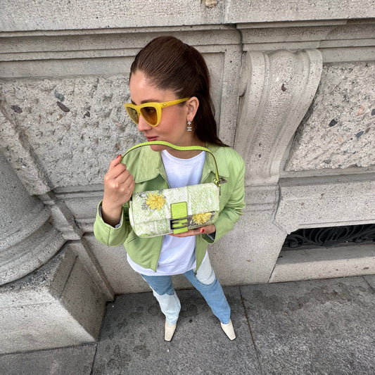 Person wearing a green jacket and yellow sunglasses on stone steps