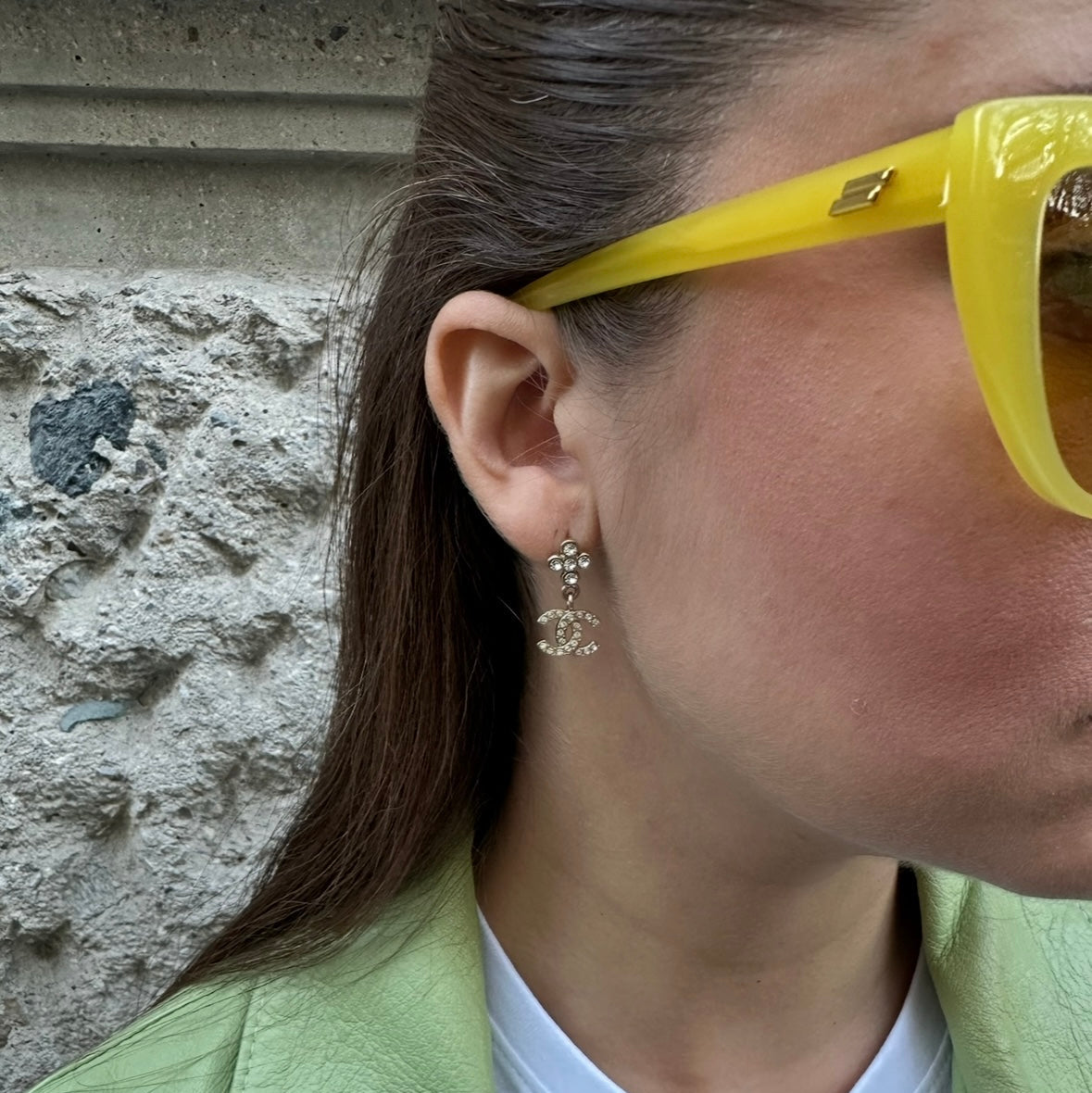 Person wearing yellow sunglasses with a stone wall background