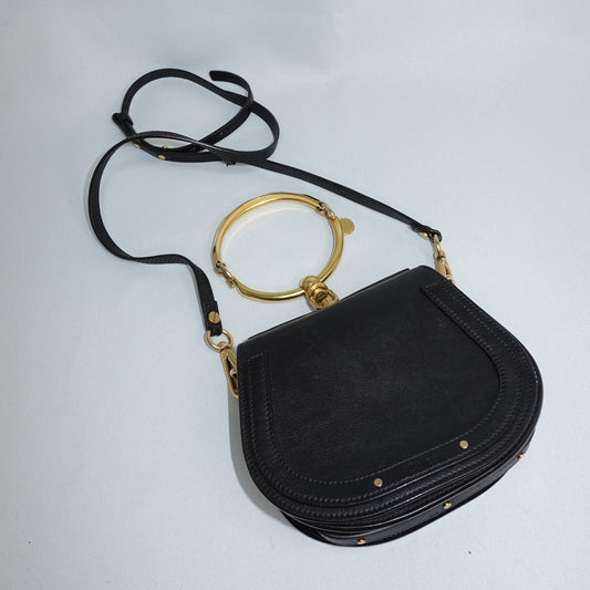 Black handbag with gold accents on a light gray background