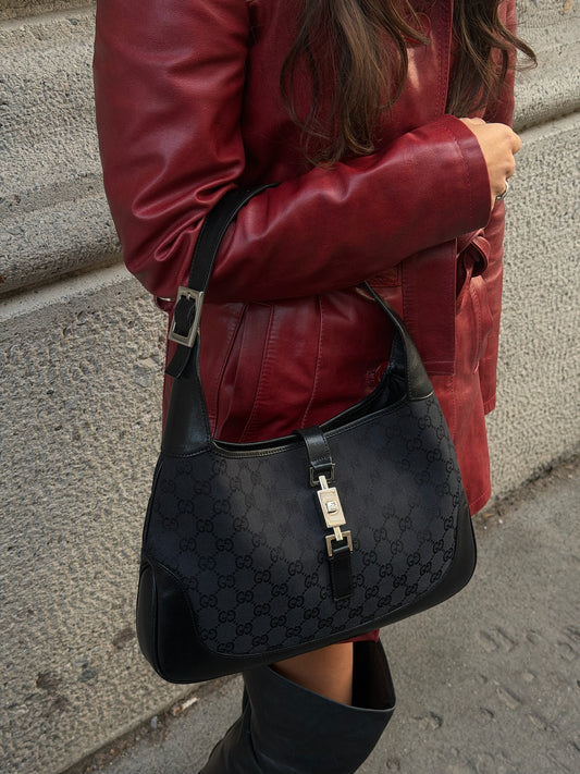 Side angle of Gucci Jackie worn picture vintage black monogram shoulder bag showing piston clasp and curved shoulder strap
