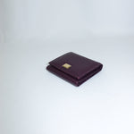 Folded purple wallet with a gold emblem on a light gray background