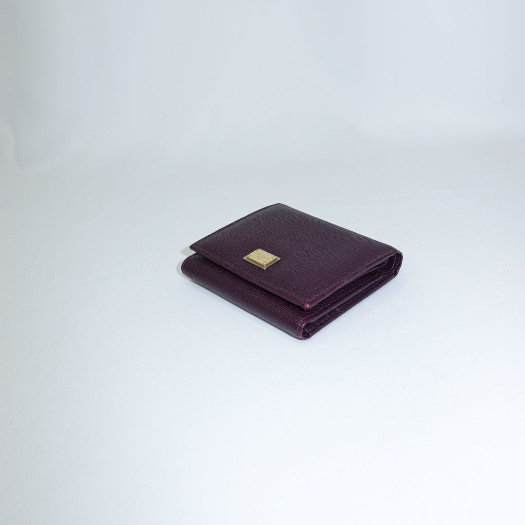 Folded purple wallet with a gold emblem on a light gray background