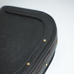 Close-up of a black leather product with gold studs on a white background
