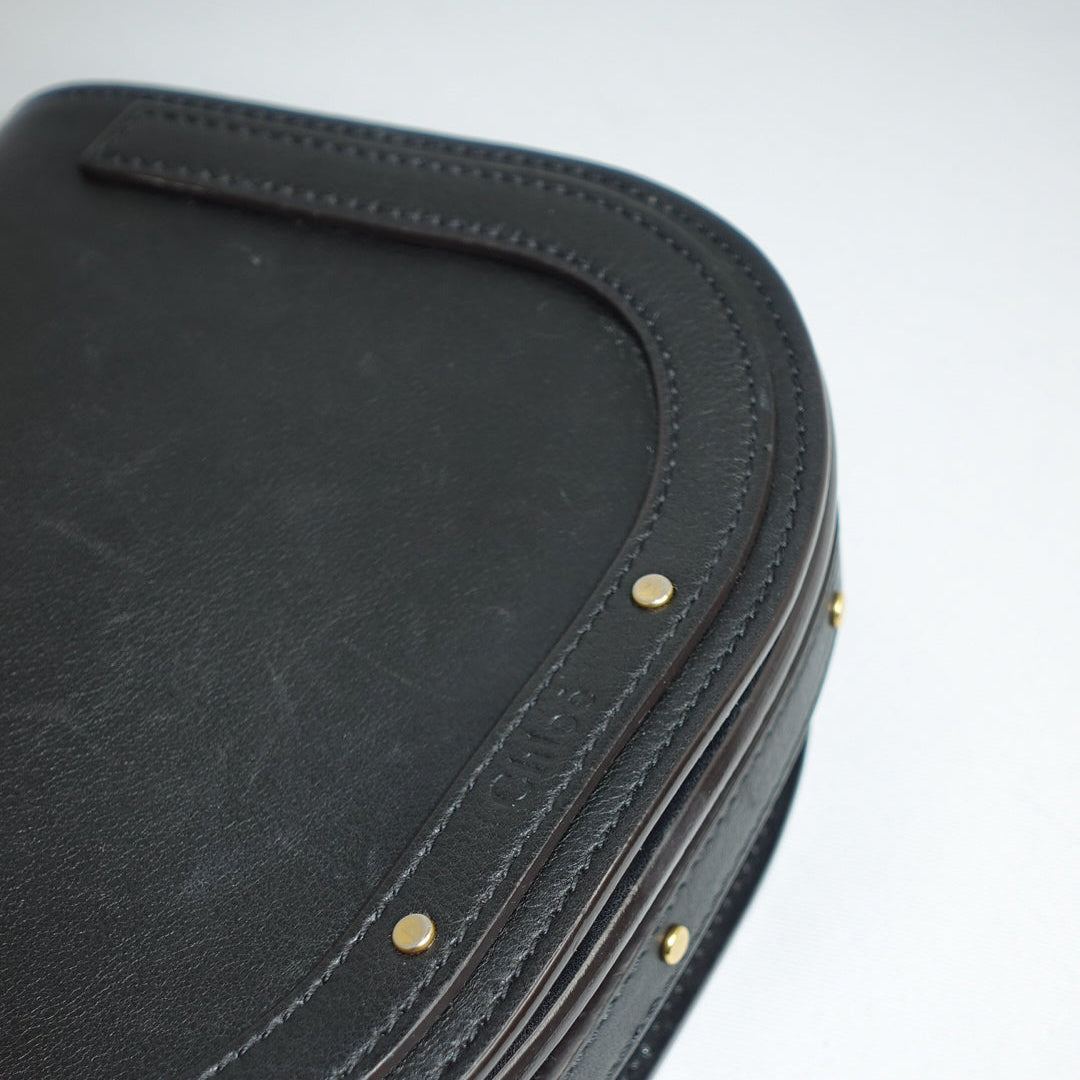 Close-up of a black leather product with gold studs on a white background