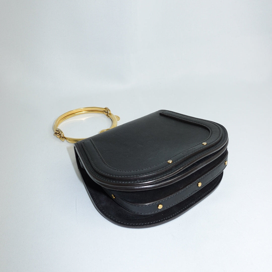 Black handbag with a gold ring on a white background