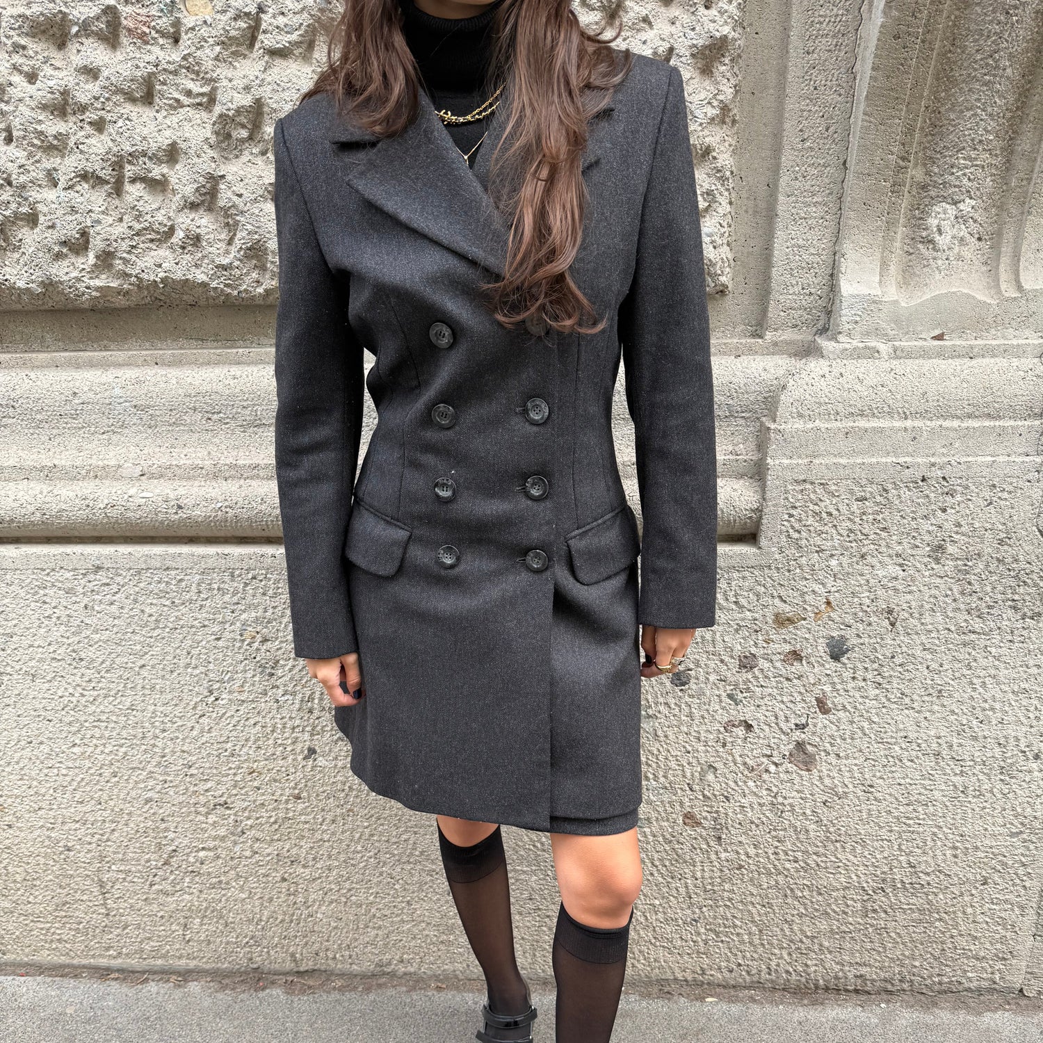 Person wearing a dark coat and black shoes on a stone staircase