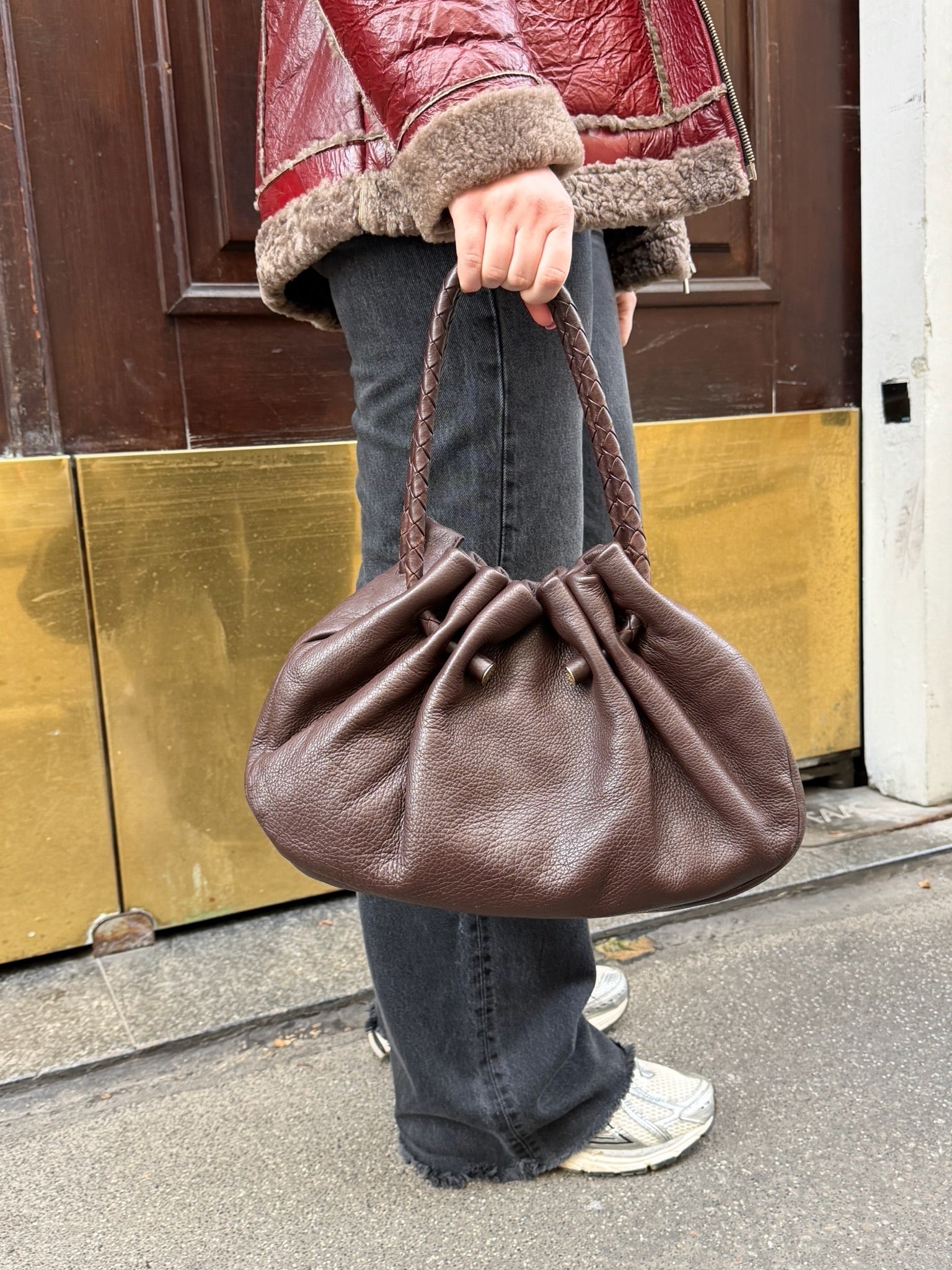 Side profile of Bottega Veneta brown hobo bag showing curved strap, leather structure, and gold hardware detail
