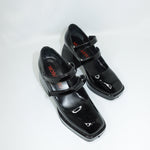Black patent leather shoes with strap design on a white background