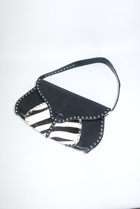 Front view of the Celine vintage shoulder bag showcasing smooth black leather contrasted with a bold zebra pony hair panel. The structured silhouette highlights the bag’s early-2000s design, with clean lines