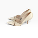 A pair of women's pointed-toe pumps in a light cream or champagne color, featuring a pleated front detail and a thin kitten heel, shown against a plain white background.