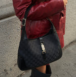 Side angle of Gucci Jackie worn picture vintage black monogram shoulder bag showing piston clasp and curved shoulder strap
