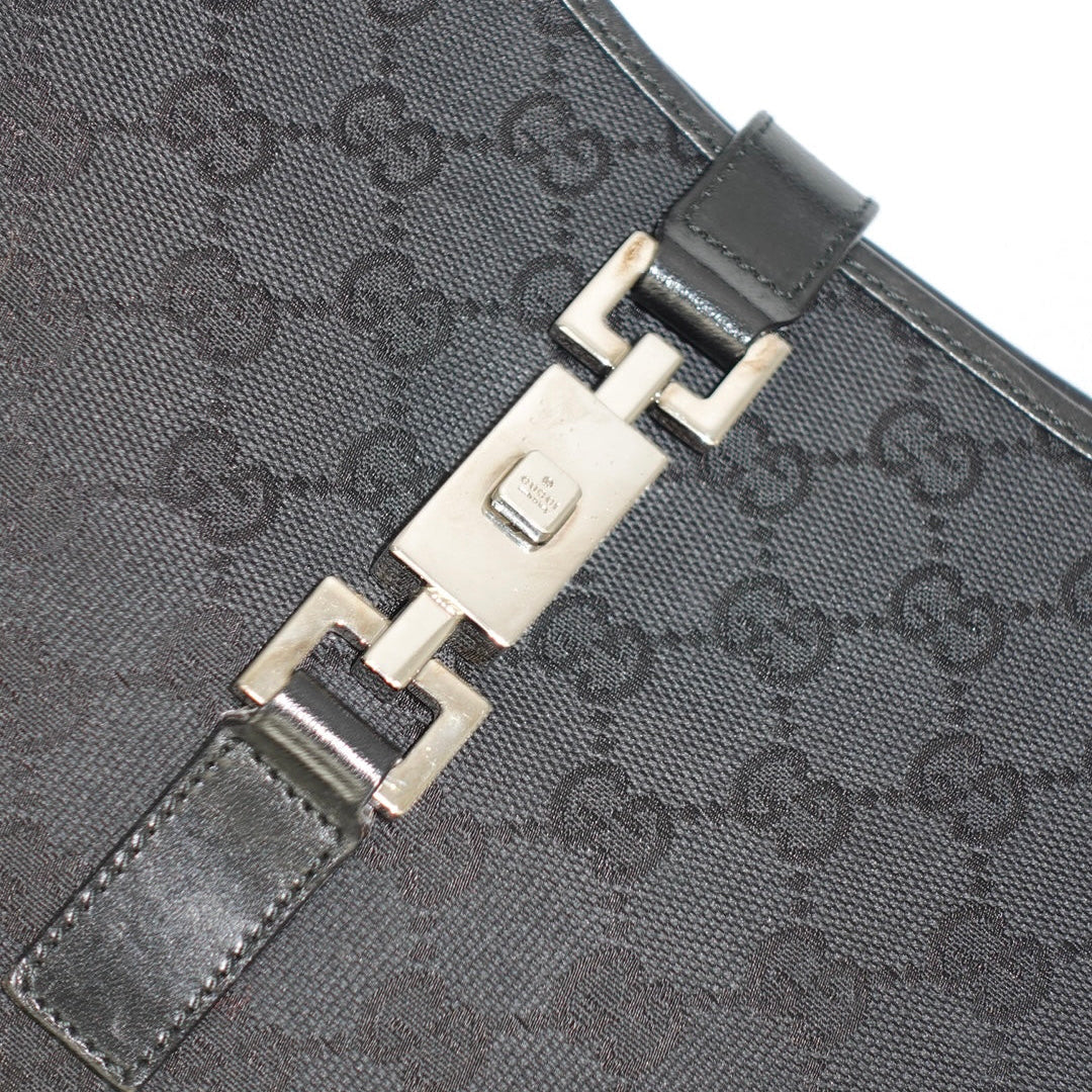 Close-up detail of Gucci Jackie bag silver hardware and black GG canvas pattern with leather edging