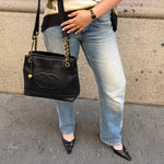 Chanel Black Caviar Tote Bag worn side view with oversized CC logo and gold chain straps