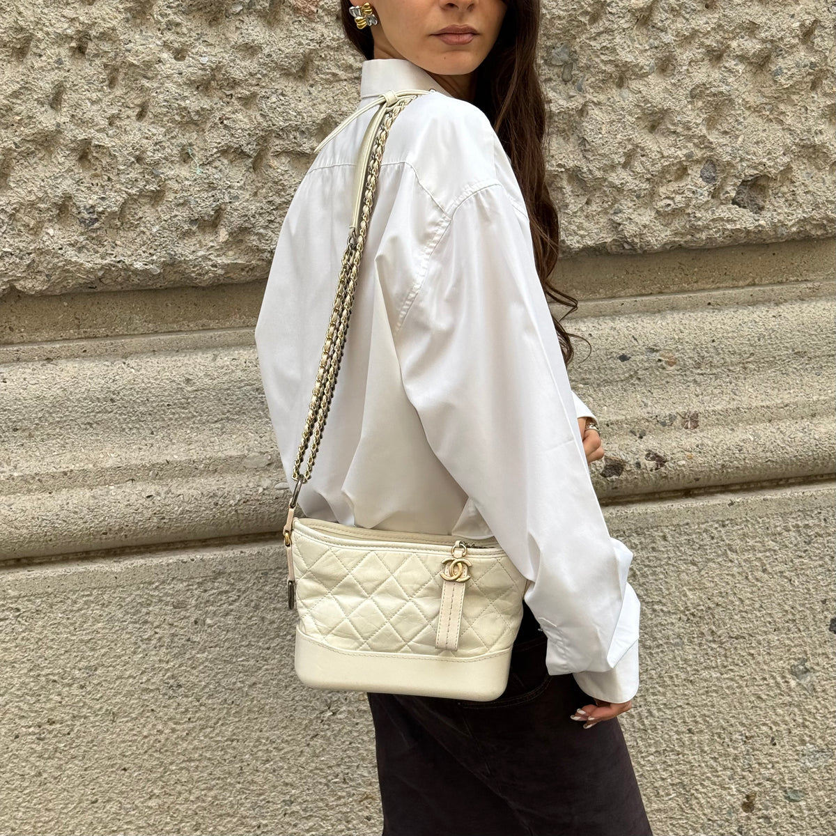 Chanel Gabrielle white leather Hobo Bag worn over the shoulder showing signature chain strap and silhouette