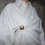 Vintage Chanel gold CC logo brooch worn on a ruched shirt showing statement styling