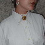 Vintage Chanel gold CC logo brooch worn on a shirt collar