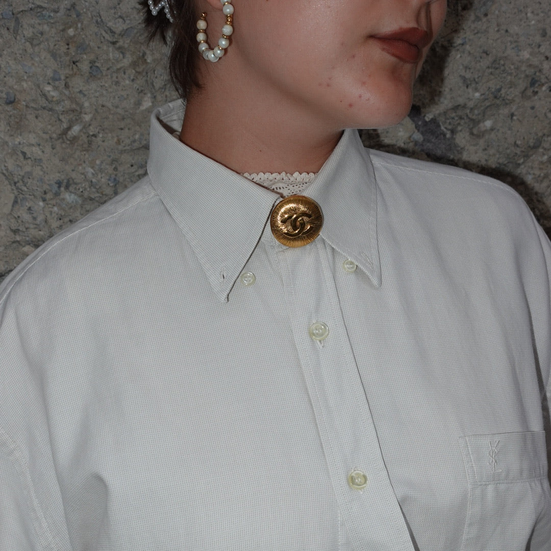 Vintage Chanel gold CC logo brooch worn on a shirt collar