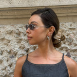 Model wearing vintage Christian Dior oval silver sunglasses with slim tinted lenses and minimalist Y2K-inspired design.