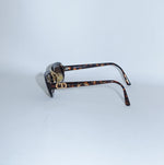Side profile of Christian Dior tortoiseshell sunglasses showcasing the signature gold CD logo on the temple.