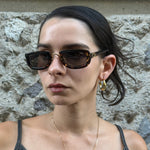 Model wearing Christian Dior tortoiseshell rectangular sunglasses with brown tinted lenses and iconic gold CD logo detail.