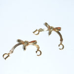 Vintage Christian Dior gold-toned ribbon bow earrings still life with dangling Dior letter charms