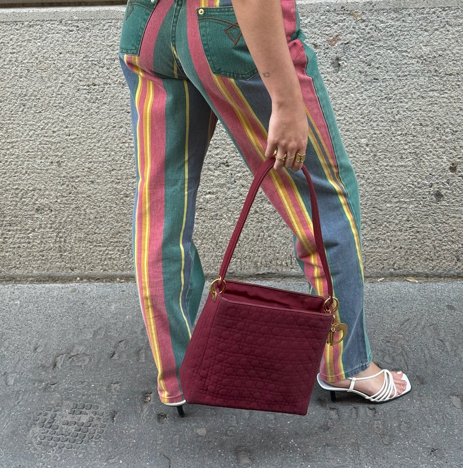 Model carrying Dior Lady Dior Cannage red leather bag with gold-tone charms and detachable shoulder strap.