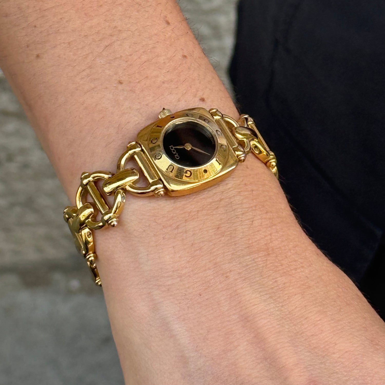 Close-up of Gucci 6400L gold-toned black dial watch in very good condition, showing the dial and case details.