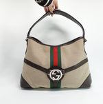 Gucci beige Reins Hobo Bag in GG canvas and brown leather, styled in a still life product photograph