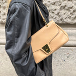 Gucci Lady Lock beige leather bag worn over the shoulder, showcasing its elegant silhouette and leather finish