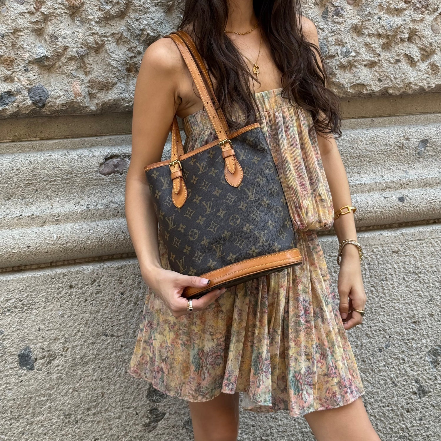 Model carrying a vintage Louis Vuitton Monogram Bucket Bag in coated canvas with Vachetta leather straps