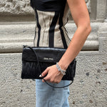 Miu Miu Maxi Matelassé Pochette in black leather featuring the iconic quilted design and zip-top closure.
