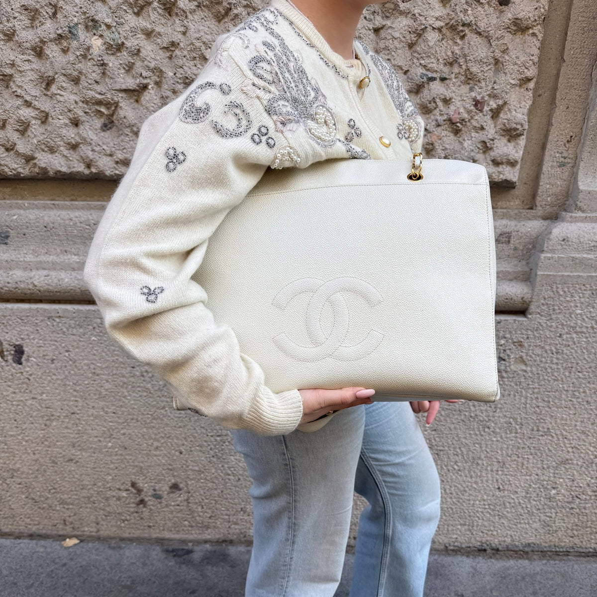 My Vintage Attire Chanel white caviar leather maxi tote bag with embossed CC logo and gold chain straps held by a person