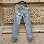 Back view of Prada light blue slim-fit jeans highlighting the minimalist back pockets, subtle fading, and signature Prada leather logo patch.