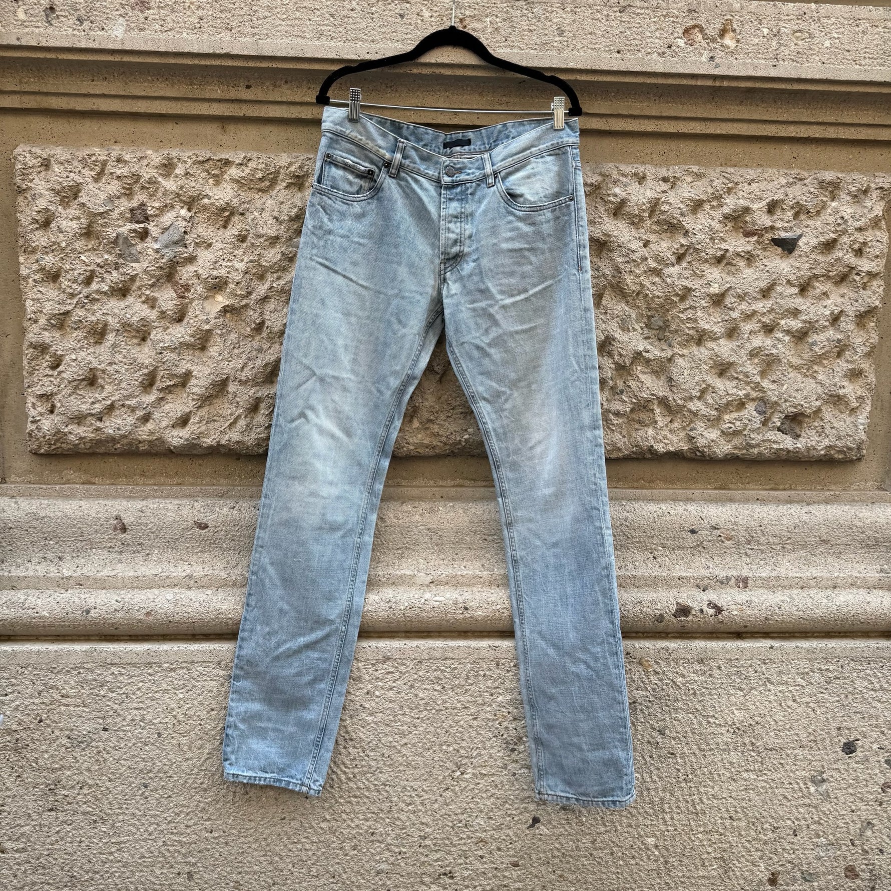 Front view of Prada light blue slim-fit jeans featuring a classic five-pocket design, vintage wash, and minimalist luxury styling.