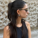 Side profile of Prada tortoiseshell cat-eye sunglasses featuring slim acetate temples with subtle Prada logo detail.