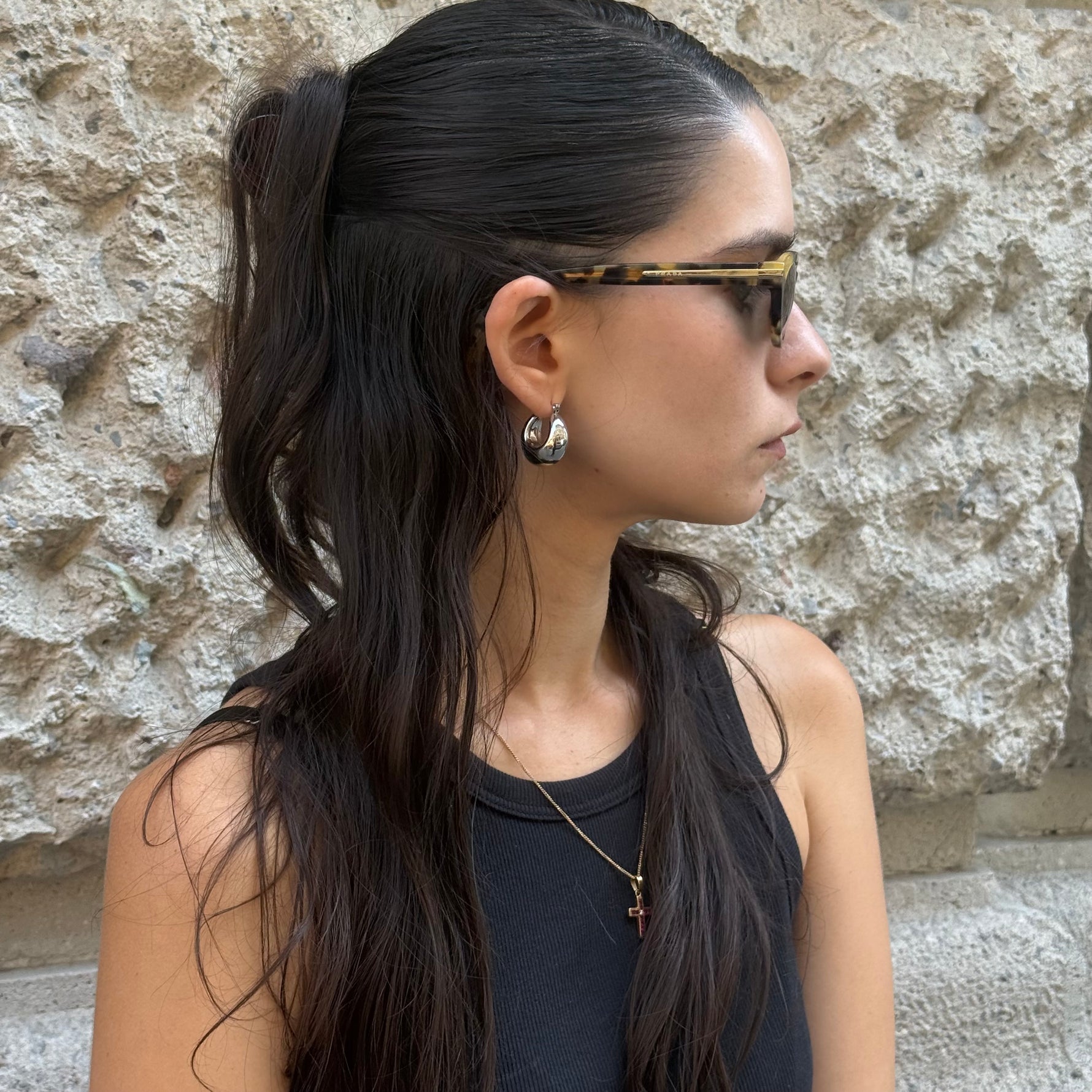 Side profile of Prada tortoiseshell cat-eye sunglasses featuring slim acetate temples with subtle Prada logo detail.