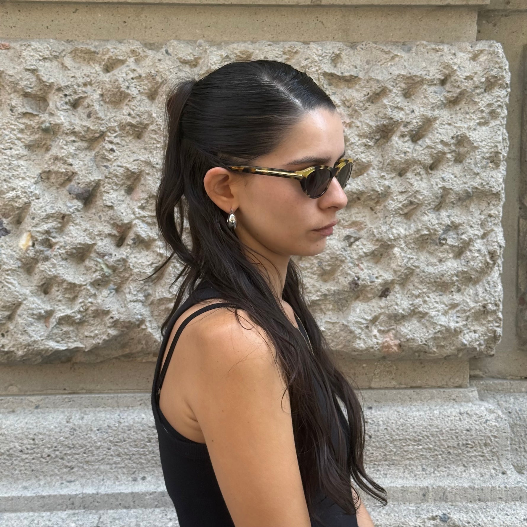 Model wearing Prada tortoiseshell cat-eye sunglasses with dark tinted lenses and elegant slim-frame design.