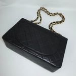 Back view of a vintage Chanel black quilted leather jumbo flap bag featuring the signature diamond quilting, rear slip pocket, and classic structured silhouette.