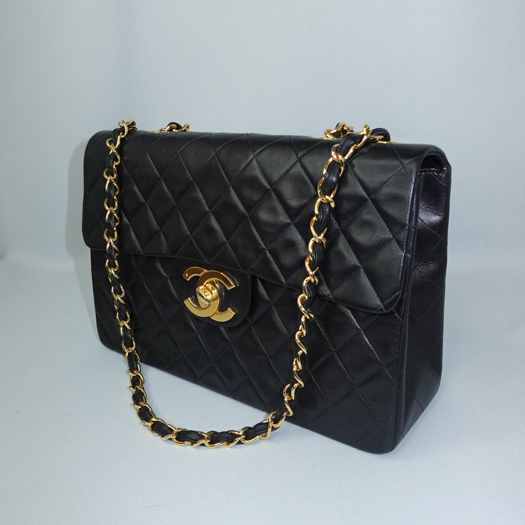 Side view of a vintage Chanel black quilted jumbo flap bag showcasing its structured silhouette, diamond quilting, and gold-tone chain straps.