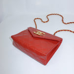 Side view of a vintage Chanel red quilted leather bag showcasing its structured silhouette, quilted finish, and gold-tone chain strap.