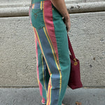 Side view of vintage green rainbow print straight jeans showcasing colorful striped side panels and relaxed mom fit silhouette.