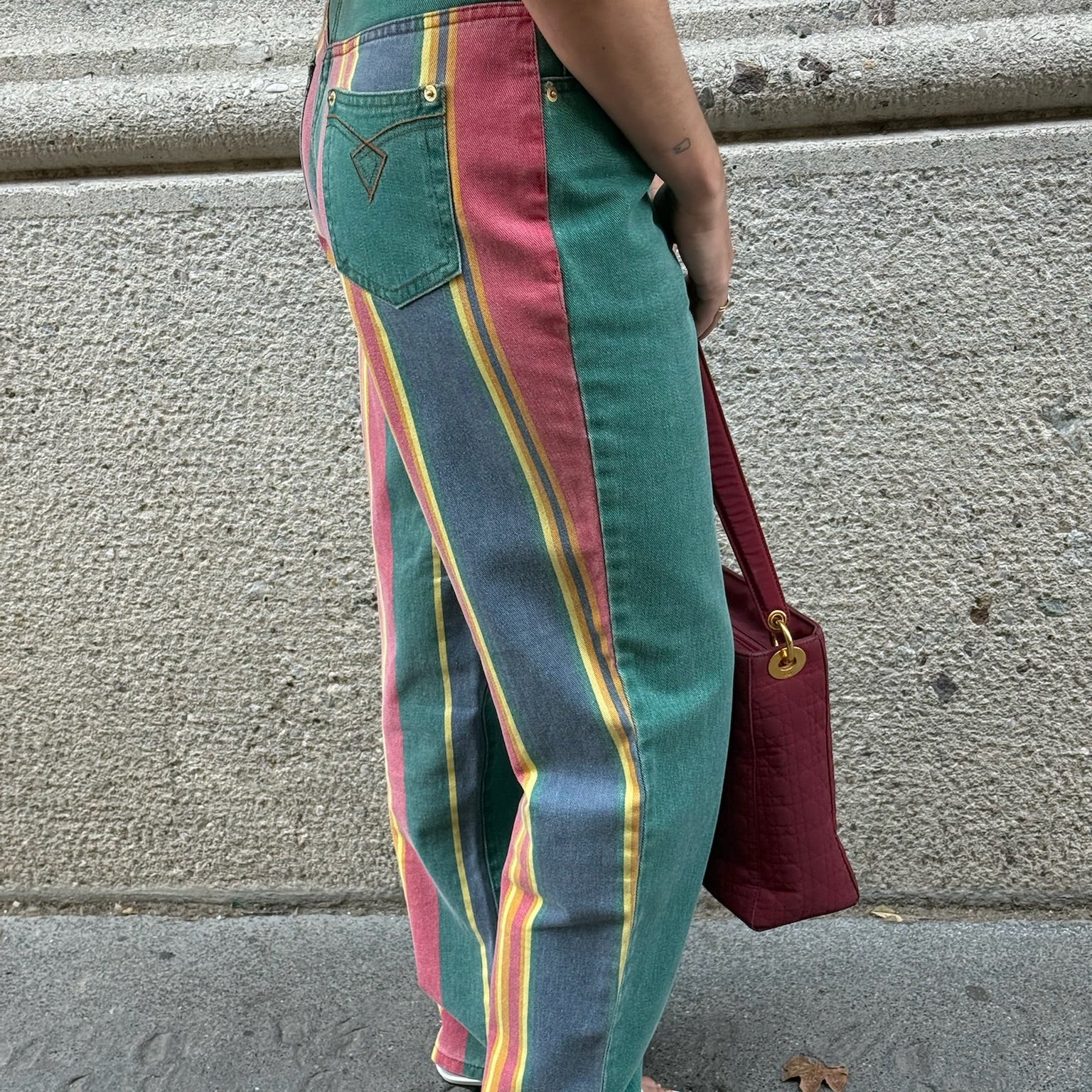 Side view of vintage green rainbow print straight jeans showcasing colorful striped side panels and relaxed mom fit silhouette.