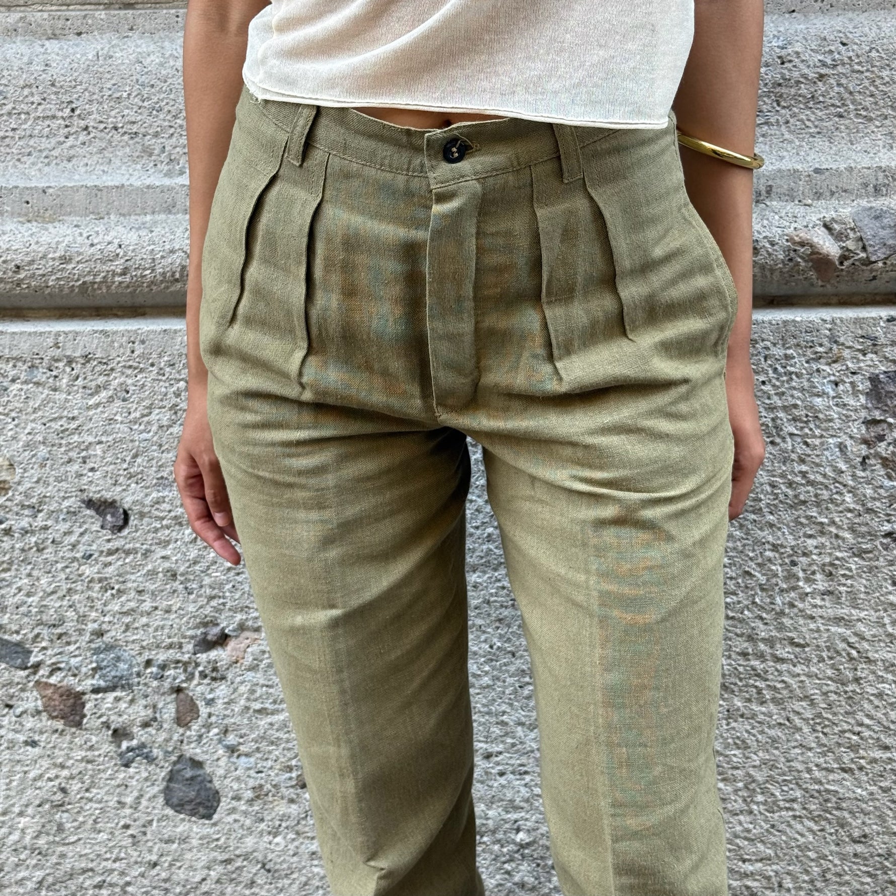 Close-up detail of vintage olive green tailored pants featuring front pleats, waistband construction and premium tailoring.
