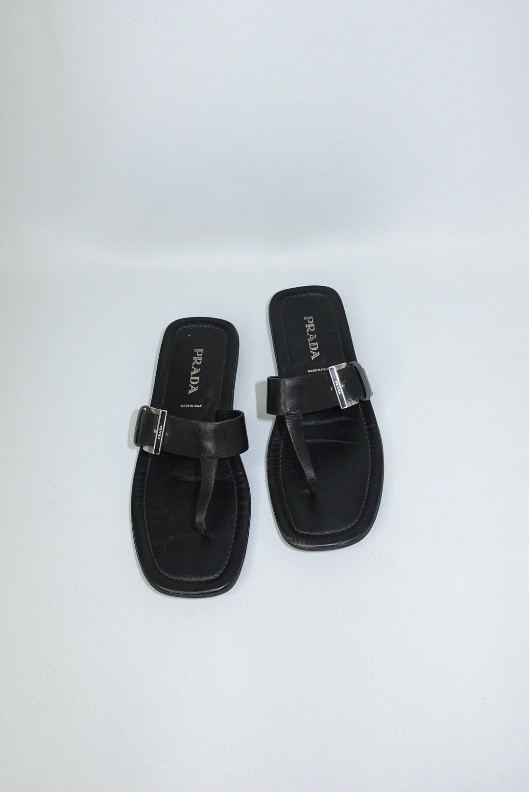 Vintage Prada black leather sandals front view featuring statement silver-toned buckle detail