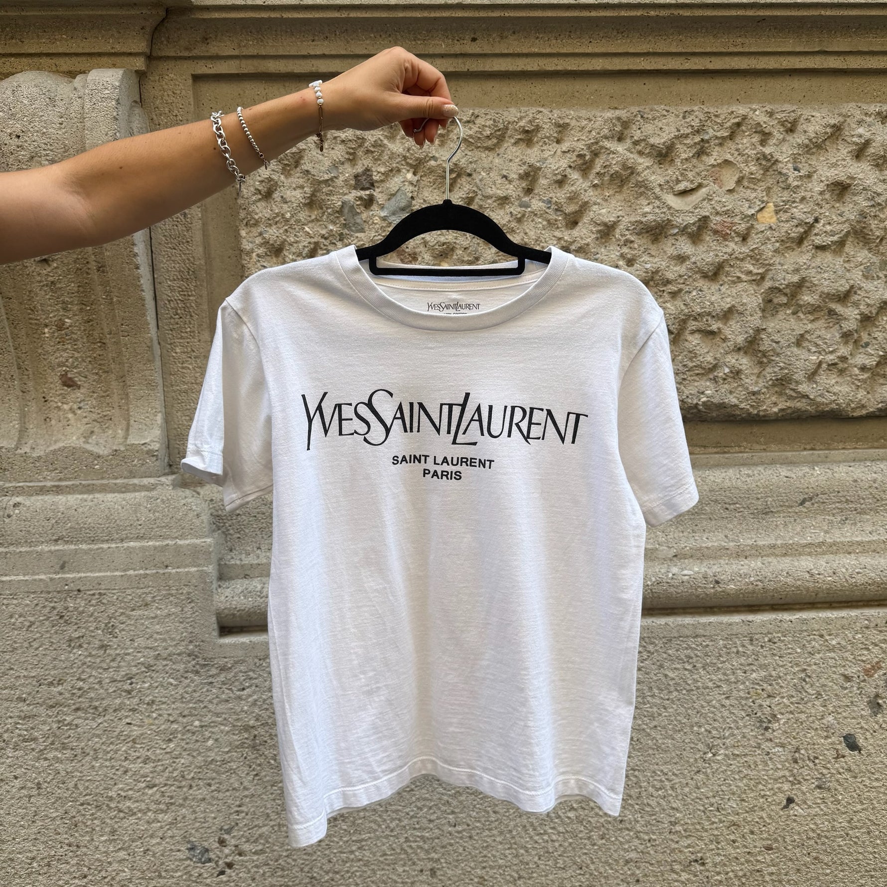 Front view of a Yves Saint Laurent white cotton T-shirt featuring the iconic YSL Paris logo print and a classic crew neck silhouette.