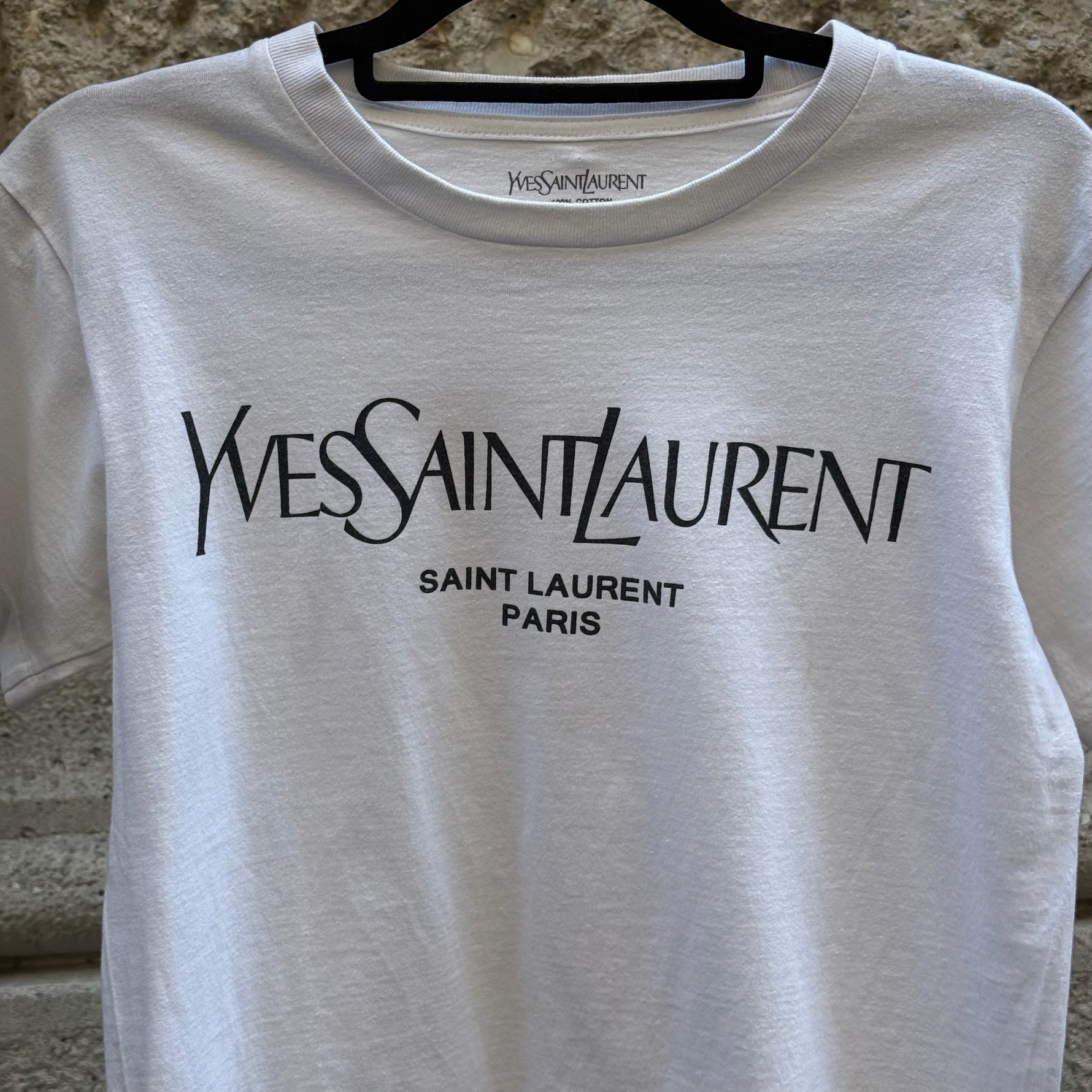 Close-up of the Yves Saint Laurent Paris logo printed on a white cotton T-shirt, highlighting the iconic designer branding and premium craftsmanship.